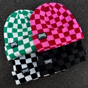 May include: Four beanies in green and white, pink and red, black and white, and black and grey chequered patterns. Each beanie has a small black tag with the word "Victous" in white script.