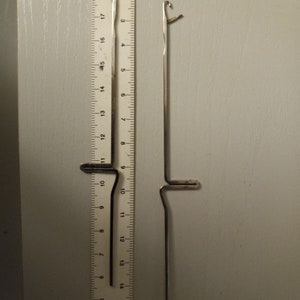 May include: Two silver crochet hooks, one with a loop at the top and the other with a straight end, are shown next to a ruler. The ruler is marked in inches.