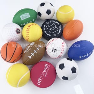 May include: A collection of various sports-themed stress balls, including a green football, a soccer ball, a tennis ball, a golf ball, a baseball, a basketball, and a brown football. Also included is a black round item with the text "JIMMY JOHN'S SANDWICHES".