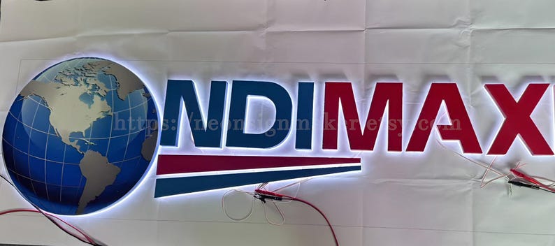 May include: A white illuminated sign with the text "ONDIMAX" in blue and red letters. A globe with a blue and grey map of the world is on the left side of the sign.