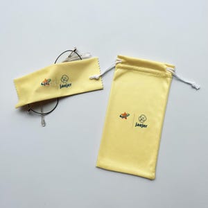 May include: Two yellow microfiber cleaning cloths with a drawstring pouch. The cloths have the logo "Jaejer" and a star with a circle around it. The pouch has the same logo and a white drawstring.
