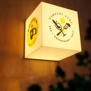 Może przedstawiać: Biały kwadratowy znak z żółtym kołem po lewej stronie, na którym widnieje napis "Coffee Spot" i większym żółtym kołem po prawej stronie, na którym widnieje napis "Company Name Bar. Restaurant. Hall".