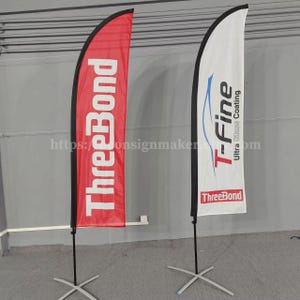 May include: Two feather flags with black poles and cross bases. One flag is red with the white text "ThreeBond". The other is white with the blue text "T-Fine Ultra Glass Coating" and the "ThreeBond" logo.