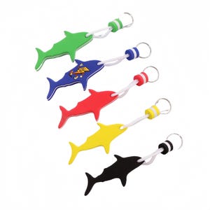Pode incluir: Uma coleção de chaveiros em forma de tubarão em várias cores: verde, azul, vermelho, amarelo e preto. Cada chaveiro tem um cordão branco e um anel. O tubarão azul tem um gráfico de um raio. Um acessório divertido.