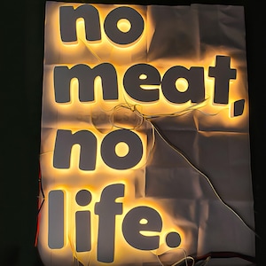May include: White illuminated letters spelling "no meat, no life" on a white background.