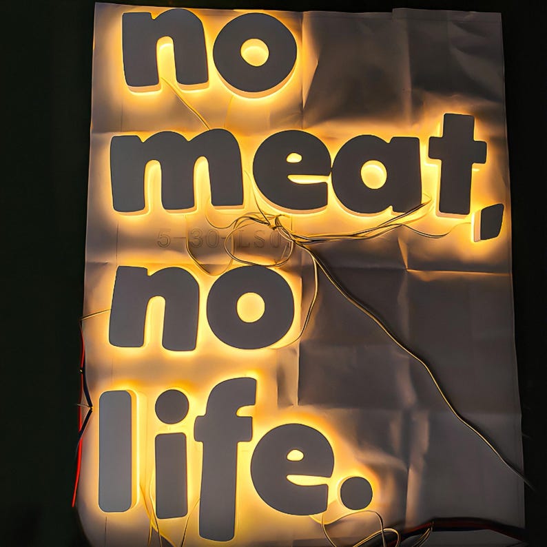 May include: White illuminated letters spelling "no meat, no life" on a white background.