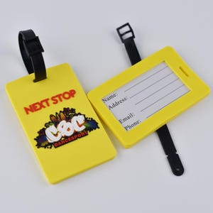 Può includere: Due etichette per bagagli rettangolari giallo brillante con cinturini in silicone nero. Un'etichetta mostra il testo rosso NEXT STOP e un logo colorato C&C DANCESPORT. L'altra mostra una scheda informativa bianca con righe per Nome, Indirizzo, Email e Telefono.