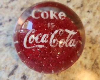 Fermacarte vintage con la scritta "Coke is Coca-Cola" (La Coca-Cola è la Coca-Cola
