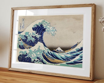 Op de afbeelding: Een ingelijste print van een beroemde Japanse houtsnede, "De Grote Golf voor Kanagawa" van Katsushika Hokusai. De print toont een grote golf die over drie boten breekt, met de berg Fuji op de achtergrond.