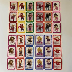 Könnte beinhalten: Eine Sammlung von vier Aufkleberbögen mit verschiedenen Cabbage Patch Kids Puppen in unterschiedlichen Outfits und Posen. Jeder Aufkleber ist mit einem gewellten Rand in den Farben Rot, Gelb, Grün, Orange, Lila und Blau versehen.