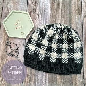 May include: Knitting pattern for a black and white checkered beanie hat. The pattern is called "RELO DESIGNS".