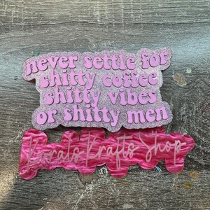 May include: Two pink acrylic signs with text. The top sign reads "never settle for shitty coffee, shitty vibes or shitty men." The bottom sign says "Karats Krafts Shop."