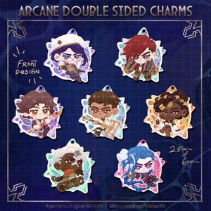 May include: A selection of double-sided Arcane character charms. Each charm showcases a different character design with a unique colour scheme. The charms are approximately 6 cm in size and have a starburst-like border. The text "Arcane Double Sided Charms" is at the top.