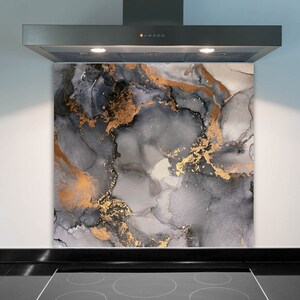 May include: A kitchen backsplash with a gray and gold abstract marble design. The backsplash is made of tempered glass and is easy to clean.