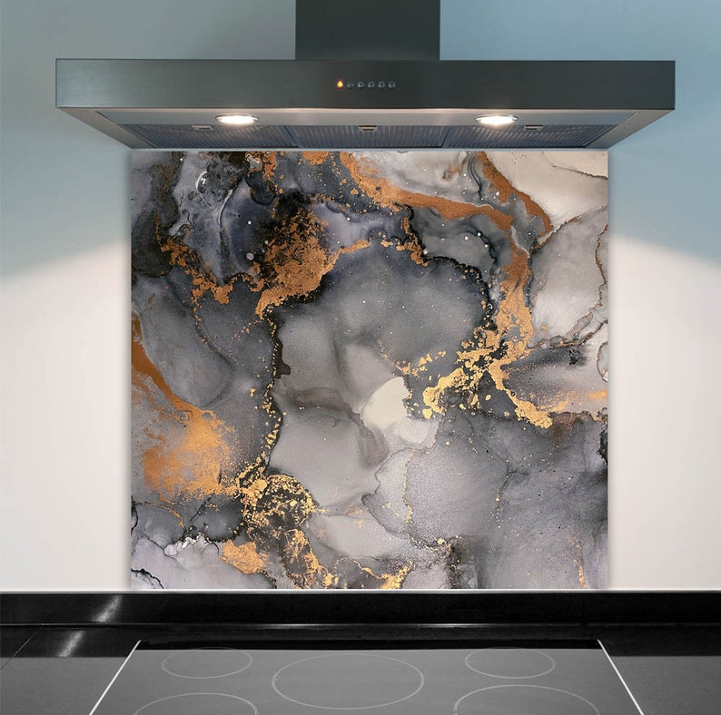 May include: A kitchen backsplash with a gray and gold abstract marble design. The backsplash is made of tempered glass and is easy to clean.