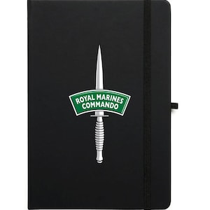 May include: Black notebook with a green and white Royal Marines Commando logo featuring a dagger. The notebook has a black elastic band closure.