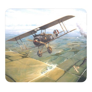 May include: A vintage World War I era biplane flies over a rural landscape. The plane is painted in a camouflage pattern with British markings. The plane is in flight, with its propeller spinning. The plane is flying over a field with a small town in the distance.