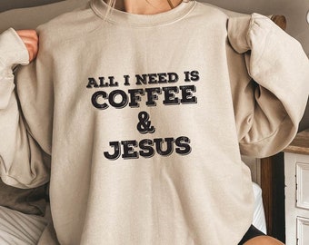 May include: A beige sweatshirt with the text "ALL I NEED IS COFFEE & JESUS" printed in black.