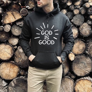 May include: Black hooded sweatshirt with a white graphic that says "GOD IS GOOD" with radiating lines around the text.