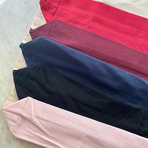 May include: Five tote bags in different colors, including red, burgundy, navy blue, black, and pink. The bags are made of canvas and are folded on top of each other.