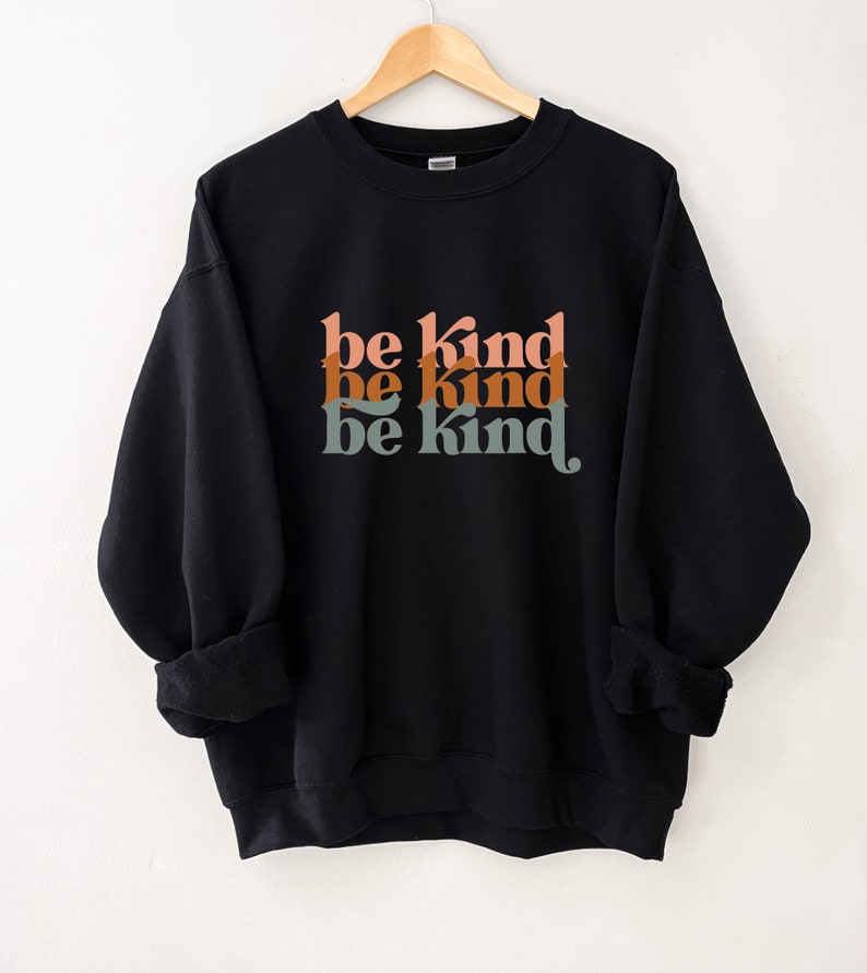 May include: Black sweatshirt with the phrase "be kind" repeated three times in a retro font with orange, brown, and green colors.