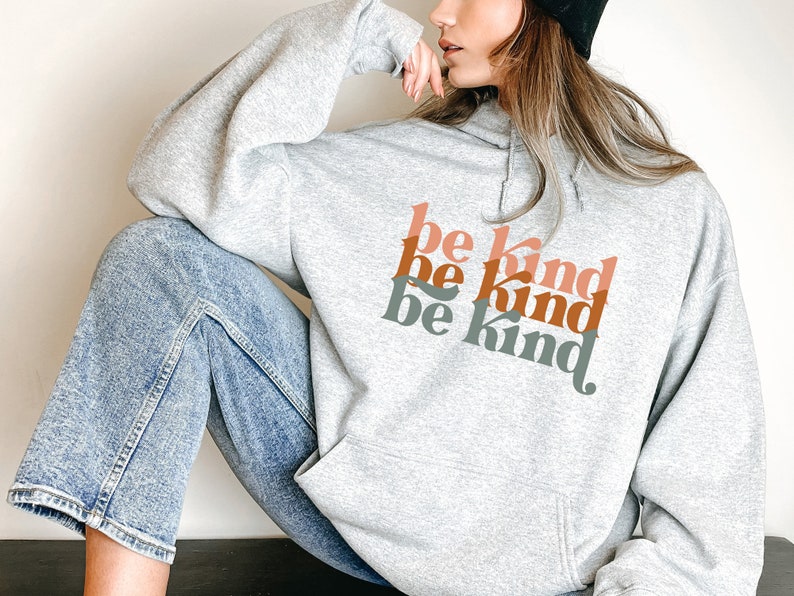 May include: A gray hoodie with the phrase "be kind" repeated three times in a retro font. The text is in shades of orange, pink, and green.
