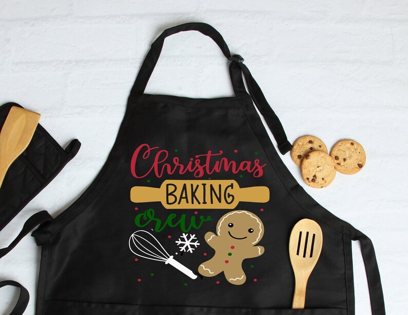 May include: Black Christmas baking apron with a gingerbread man, a rolling pin, a whisk, and the text "Christmas Baking Crew".