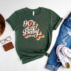 May include: A green t-shirt with the text "90's Baby" in a retro rainbow font.