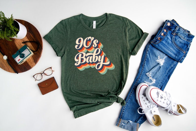 May include: A green t-shirt with the text "90's Baby" in a retro rainbow font.