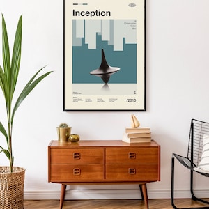 May include: A framed movie poster for the film Inception, directed by Christopher Nolan. The poster features a spinning top against a blue and white background. The text "Inception" is in a bold, sans-serif font. The year 2010 is printed in the bottom right corner.