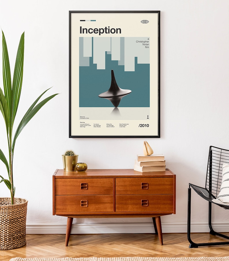 May include: A framed movie poster for the film Inception, directed by Christopher Nolan. The poster features a spinning top against a blue and white background. The text "Inception" is in a bold, sans-serif font. The year 2010 is printed in the bottom right corner.