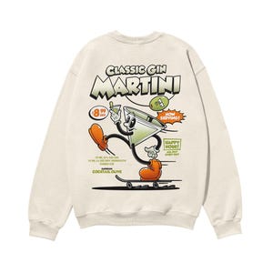 Puede incluir: Una sudadera beige con una ilustración de dibujos animados de una copa de martini en un monopatín. El texto "CLASSIC GIN MARTINI" está impreso en negrita sobre la ilustración. El texto "NOW SERVING!" está impreso en una fuente más pequeña sobre la copa de martini. El texto "HAPPY HOUR! ALL DAY EVERY DAY" está impreso debajo de la copa de martini. El texto "75 ML (2.5 OZ) GIN 15 ML (0.5 OZ) DRY VERMOUTH CUBED ICE GARNISH COCKTAIL OLIVE" está impreso debajo del monopatín.