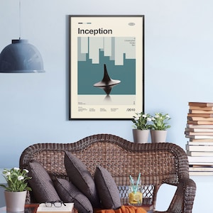 May include: A minimalist poster with a black frame featuring the movie title "Inception" in bold white text. The poster has a blue and white background with a spinning top in the center. The text "Christopher Nolan film" is in the top right corner. The year "2010" is in the bottom right corner.