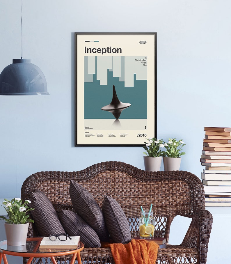 May include: A minimalist poster with a black frame featuring the movie title "Inception" in bold white text. The poster has a blue and white background with a spinning top in the center. The text "Christopher Nolan film" is in the top right corner. The year "2010" is in the bottom right corner.