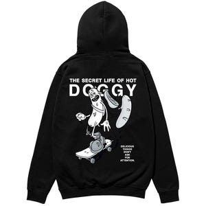 以下が含まれることがあります： スケートボードに乗ったホットドッグの漫画のキャラクターが描かれた黒いパーカー。「THE SECRET LIFE OF HOT DOGGY」と「DELICIOUS THINGS DON'T ASK FOR ATTENTION」の文字が含まれています。