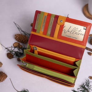 May include: A multi-colored leather wallet with a zipper closure and multiple card slots. The wallet is open and the inside is lined with a green fabric. The brand name "Walletree Genuine Leather" is visible on the inside of the wallet.
