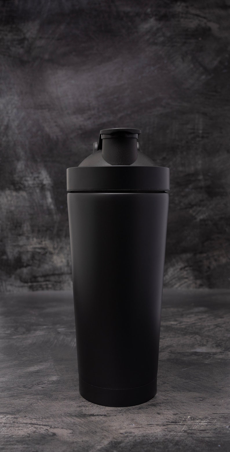 May include: A black stainless steel shaker bottle with a black lid and a black carrying loop.