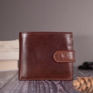 May include: A brown leather wallet with a flap closure and the word "Daddy" embossed on the front.
