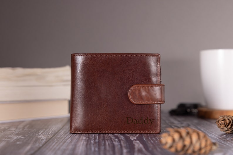 May include: A brown leather wallet with a flap closure and the word "Daddy" embossed on the front.
