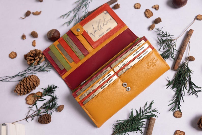May include: A yellow leather wallet with multiple card slots and a red leather interior. The wallet has a small window for displaying identification and the text "Volluto Genuine Leather" is printed on the front.