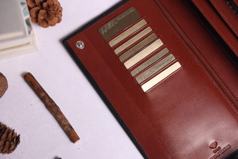 May include: A black leather wallet with multiple card slots. The wallet has a red interior and the text "Genuine Leather" is printed on the inside.