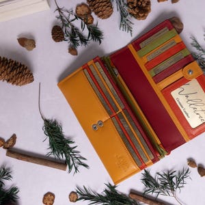 May include: A yellow and red leather wallet with multiple card slots and a snap closure. The wallet has a small window with the text "Wallet - Genuine Leather" on it.