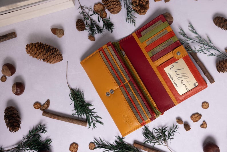 May include: A yellow and red leather wallet with multiple card slots and a snap closure. The wallet has a small window with the text "Wallet - Genuine Leather" on it.