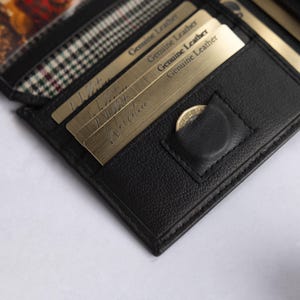 May include: A black leather wallet featuring multiple card slots, a small coin pocket with a snap closure, and a clear window section. Several gold-toned cards are inserted into the slots, each clearly marked with the text Genuine Leather.