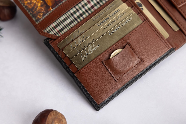 May include: A brown leather bifold wallet featuring multiple card slots, a small coin pocket, and a plaid fabric lining. Several metallic cards are inserted into the slots, each embossed with the text Genuine Leather in a repeating pattern.