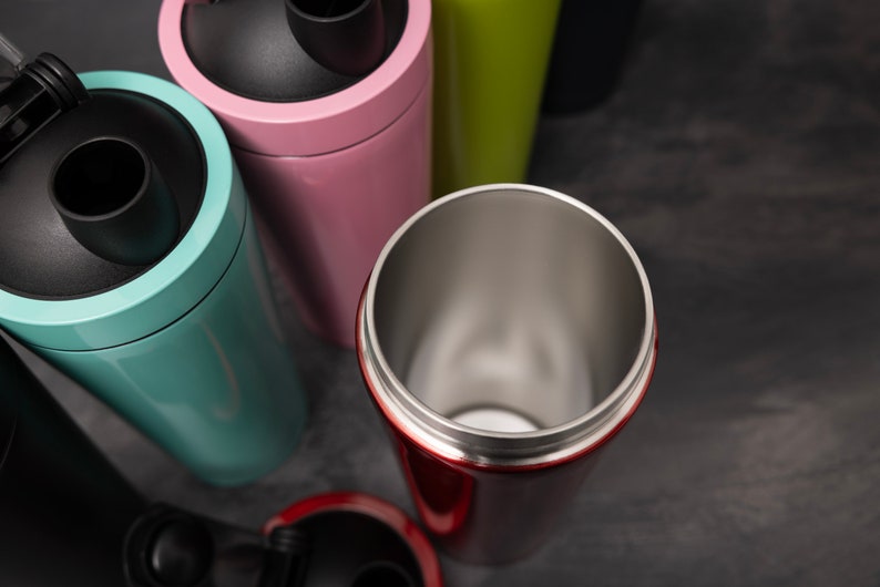 May include: A close-up of five stainless steel water bottles with different coloured lids. The bottles are arranged in a semi-circle, with the red bottle in the centre.