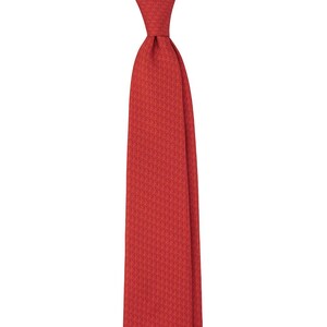 May include: A solid red necktie with a subtle geometric pattern. The tie is knotted at the top and hangs vertically against a white background. The fabric appears to be a woven material.