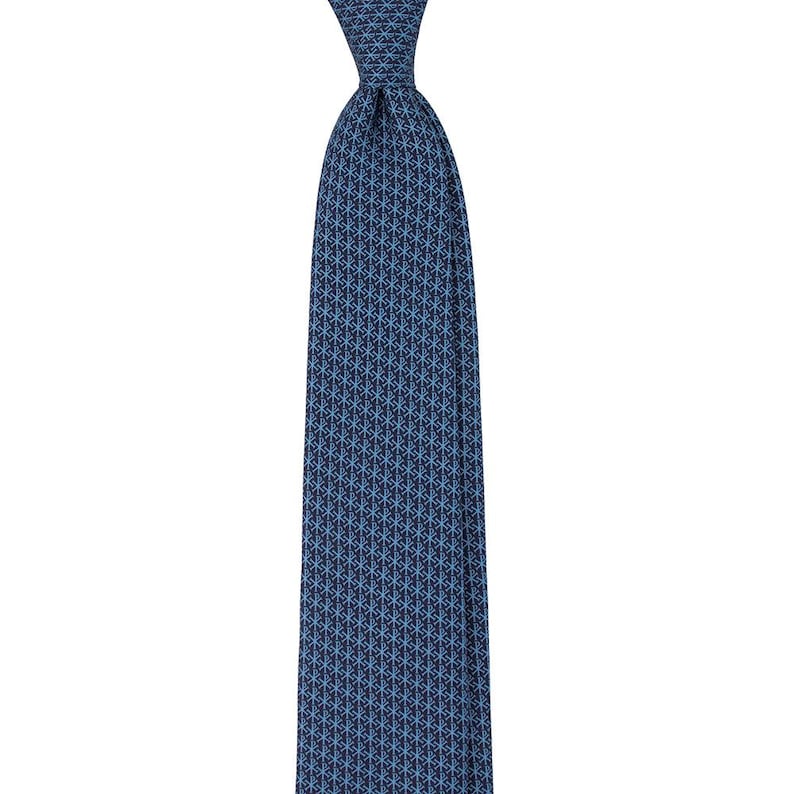 May include: A blue tie with a repeating geometric pattern. The tie is a solid color with a pattern of small, light blue shapes. The tie is knotted at the top and hangs vertically.