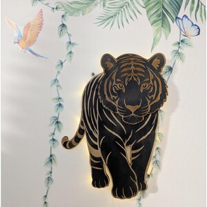 May include: A wall-mounted tiger-shaped light fixture crafted from dark wood with natural wood-toned accents. The design features intricate cutouts highlighting the tiger's stripes and facial features, with a warm glow emanating from behind the silhouette.