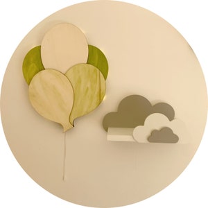 Könnte beinhalten: Ein Wandregal aus Holz in Form einer Wolke mit einem Satz Holzballons in Grün- und Beigetönen.